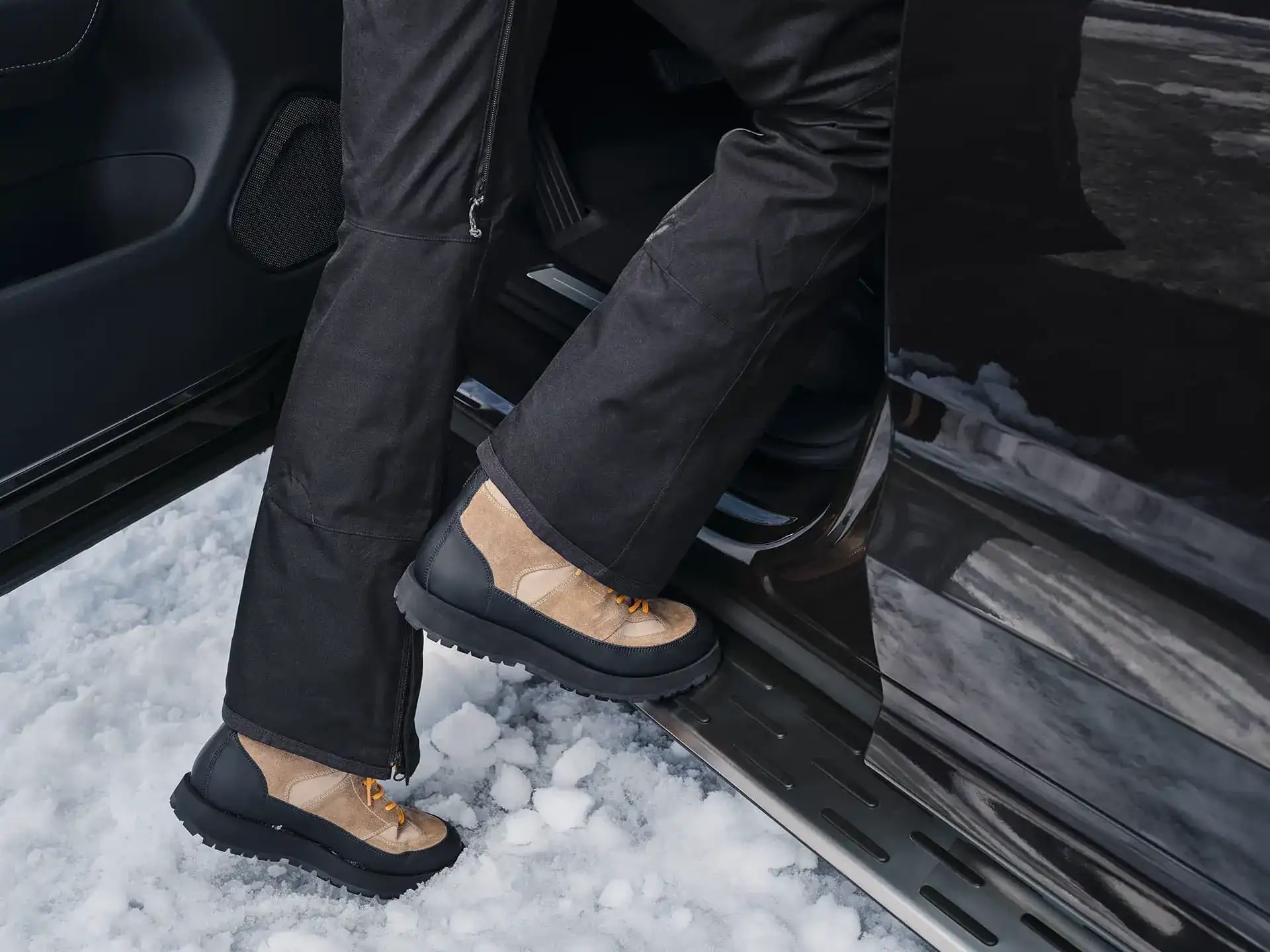 Eine Person in Winterstiefeln steigt auf ein Trittbrett in ein Volvo Fahrzeug.