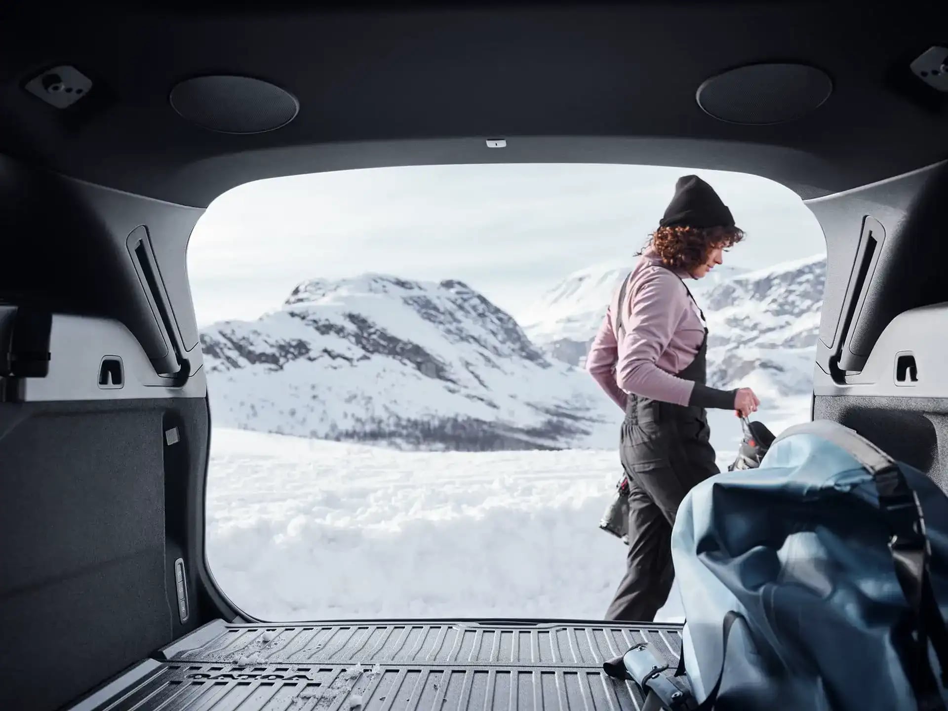 Eine Person belädt einen Volvo XC60 am Heck mit Winterausrüstung.