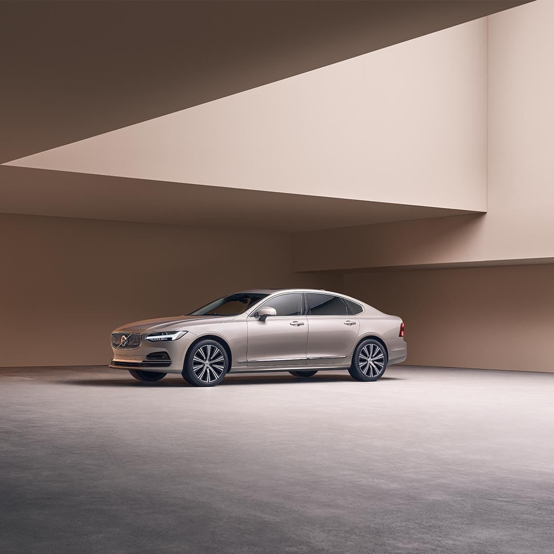 Weitwinkelaufnahme der linken vorderen Seite eines Volvo S90, der in einer grossen Betonstruktur geparkt ist.