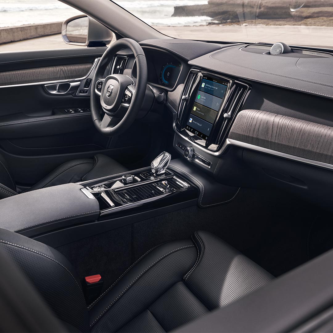 Interieur van een Volvo S90 Plug-in hybrid met bestuurdersstoel, stuur en centraal display met touchscreen.