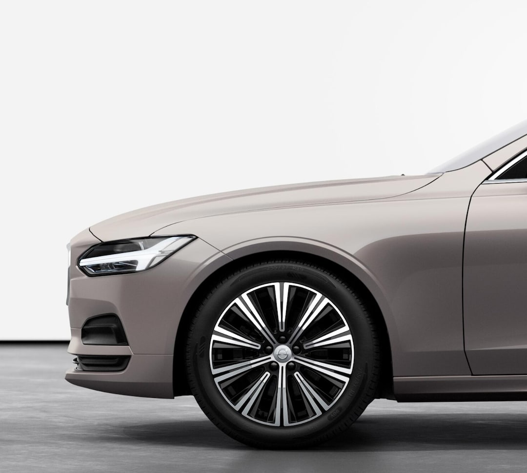 The front half of a Volvo V90 estate car in Bright Dusk, including Thor Hammer headlights and glimmering chrome hub caps.