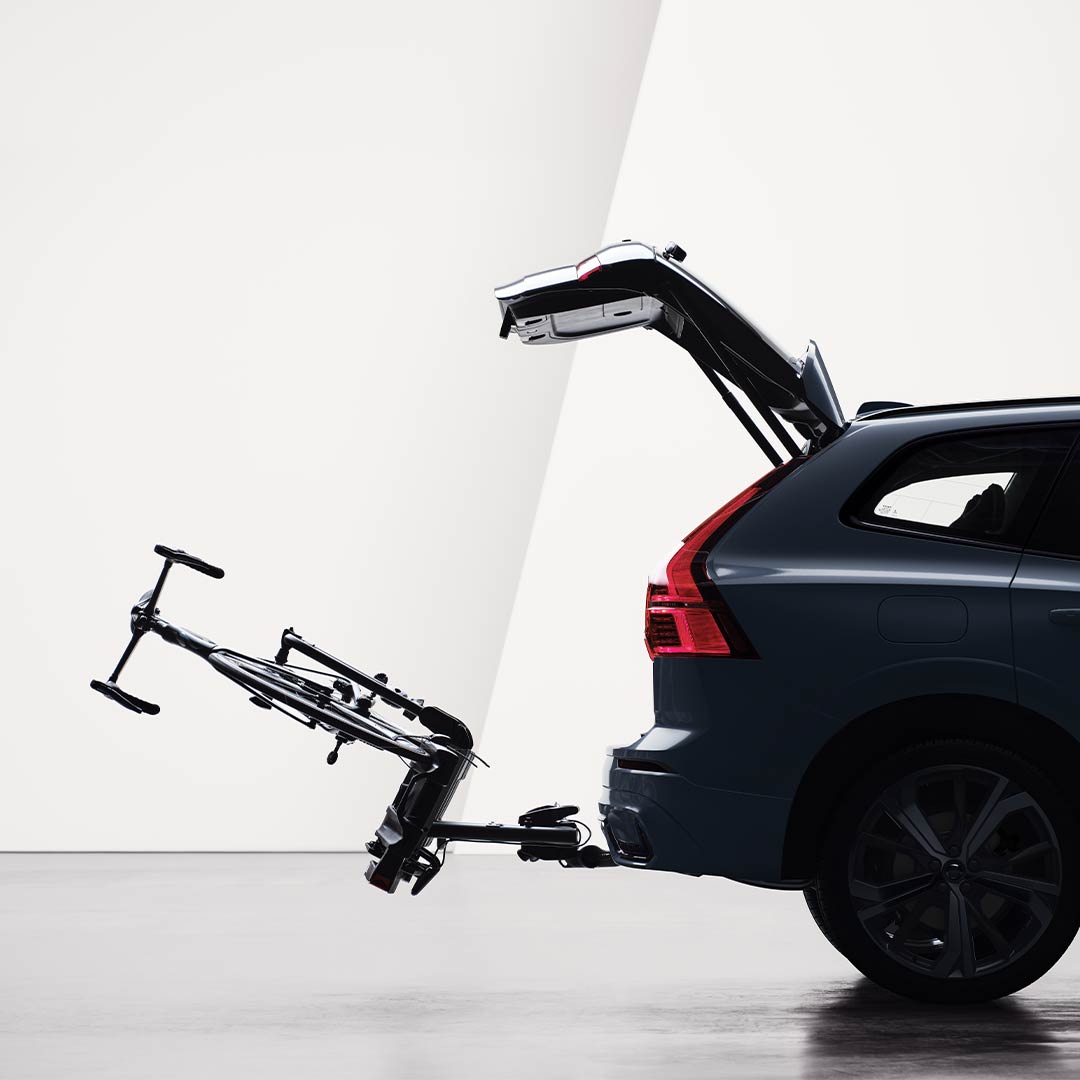 An open tailgate and a bicycle holder attached by tow bar folded down on the rear of a Volvo XC60. 