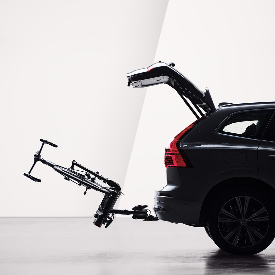 Portão traseiro aberto e porta-bicicletas fixado por gancho de reboque rebatido na traseira de um Volvo XC60.