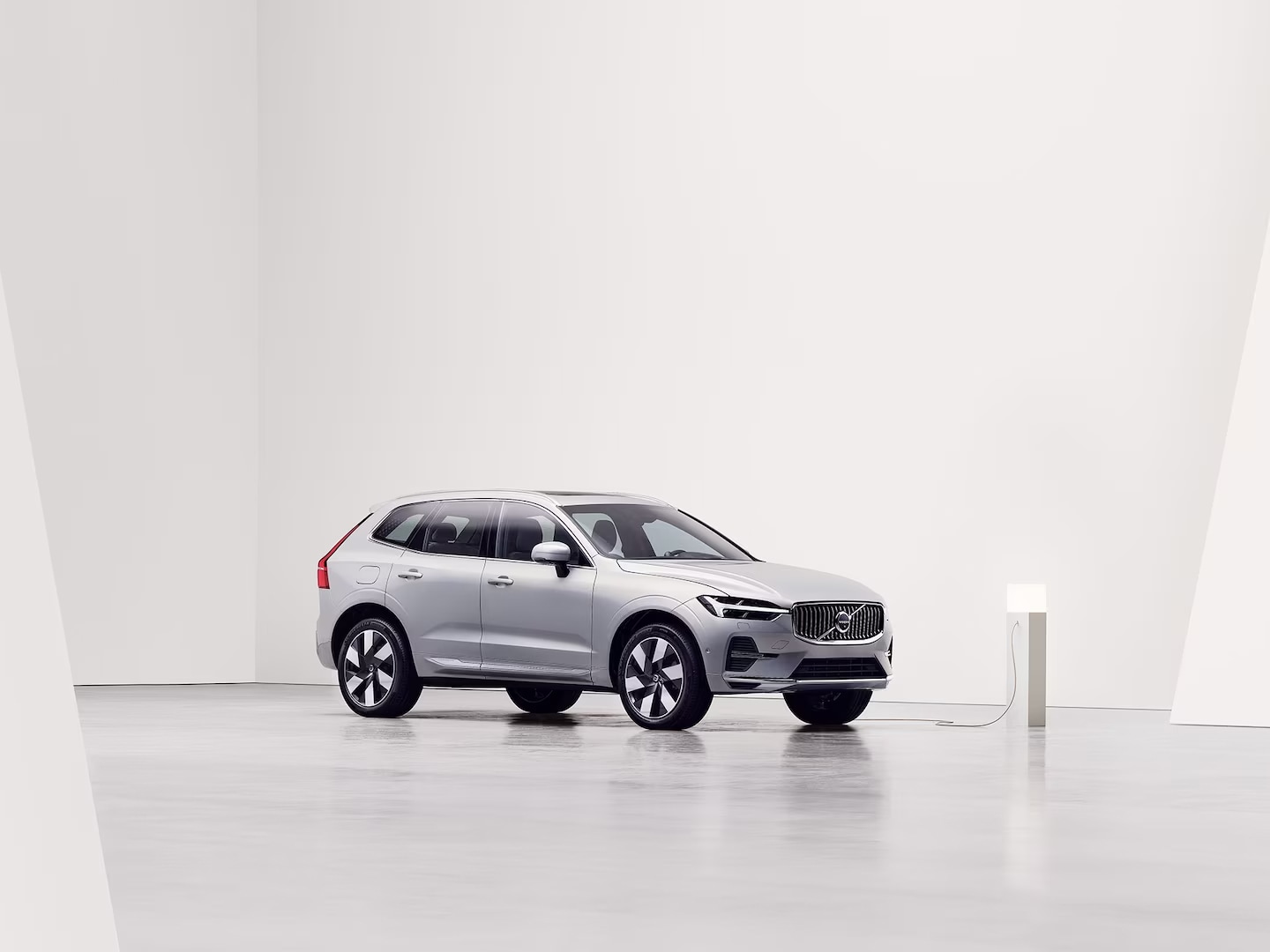 Side view of grey Volvo XC60 Recharge being charged at charging station.