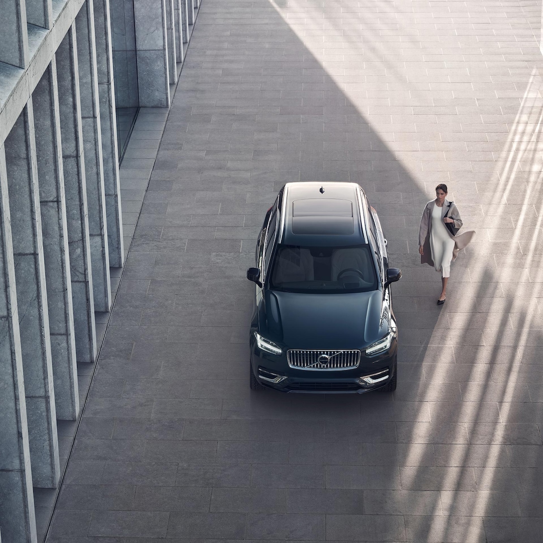 A person walking up to a Volvo XC90 Recharge plug-in hybrid. 