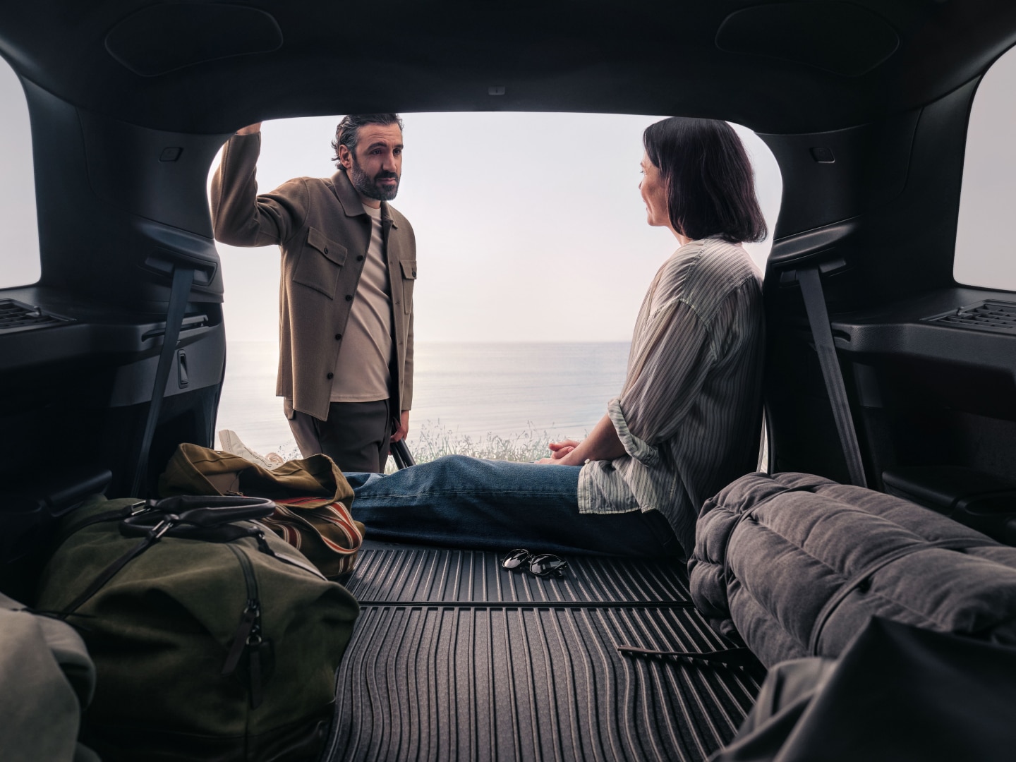 Lifestyle shot of a couple hanging out in the rear load compartment a Volvo XC90 plug-in hybrid.