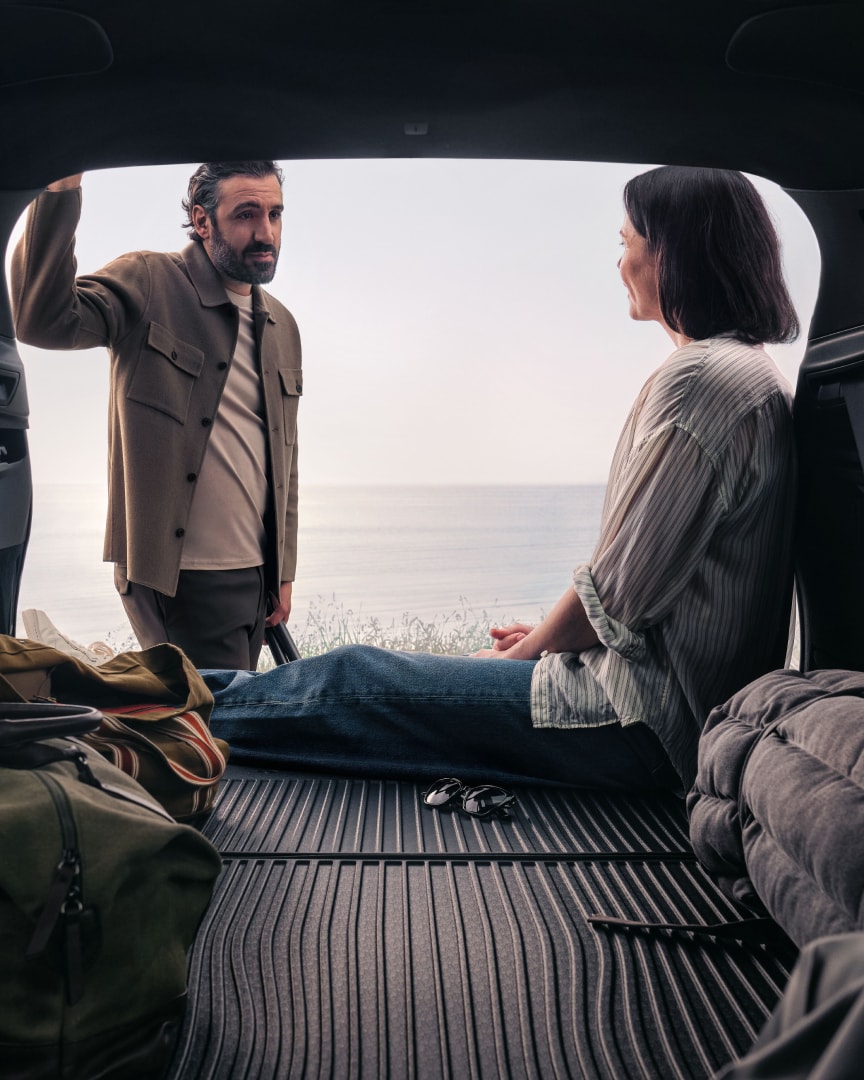 Lifestyle shot of a couple hanging out in the rear load compartment a Volvo XC90 plug-in hybrid.