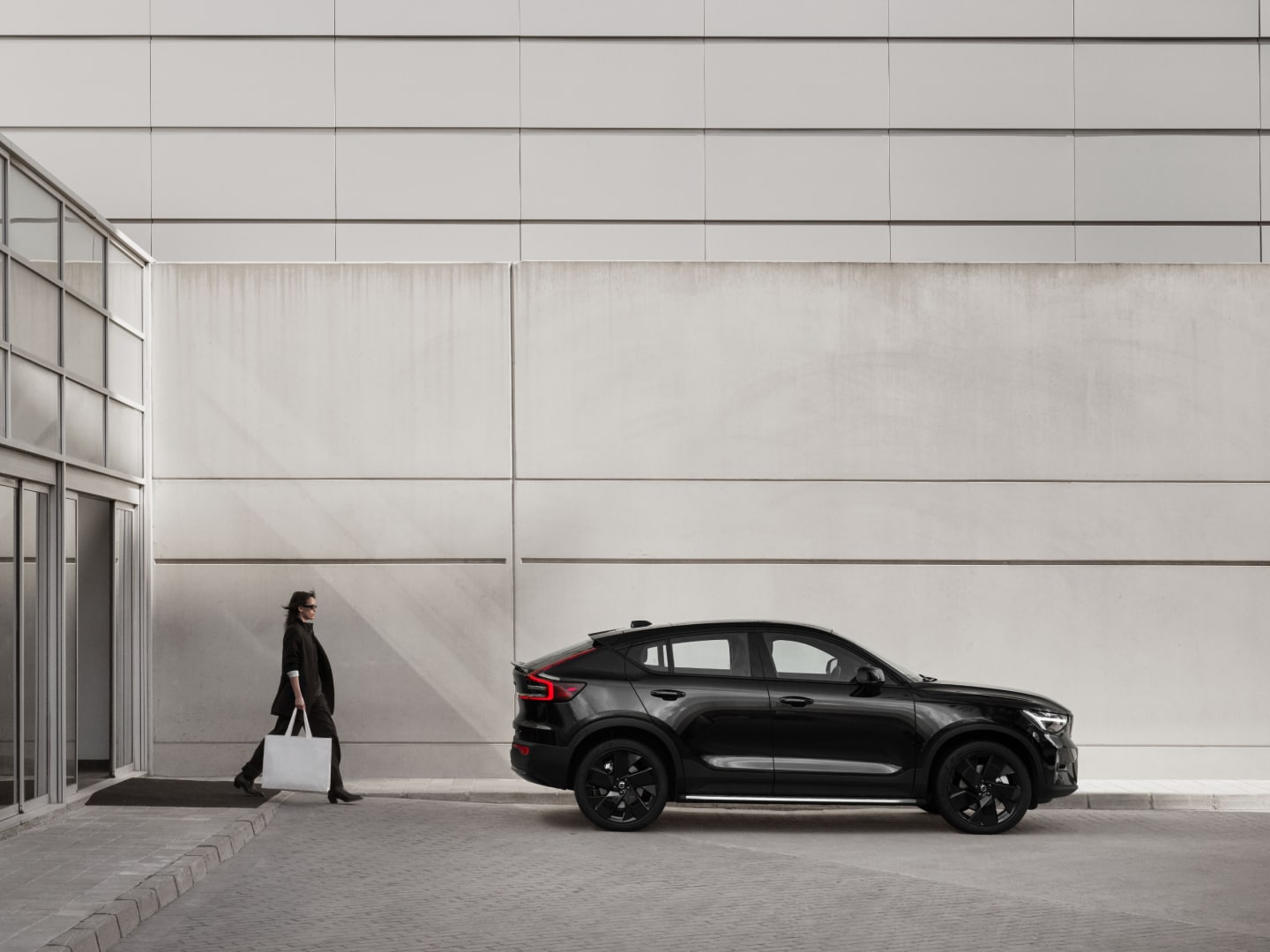 A person stands new the fully electric Volvo EC40 Black Edition.