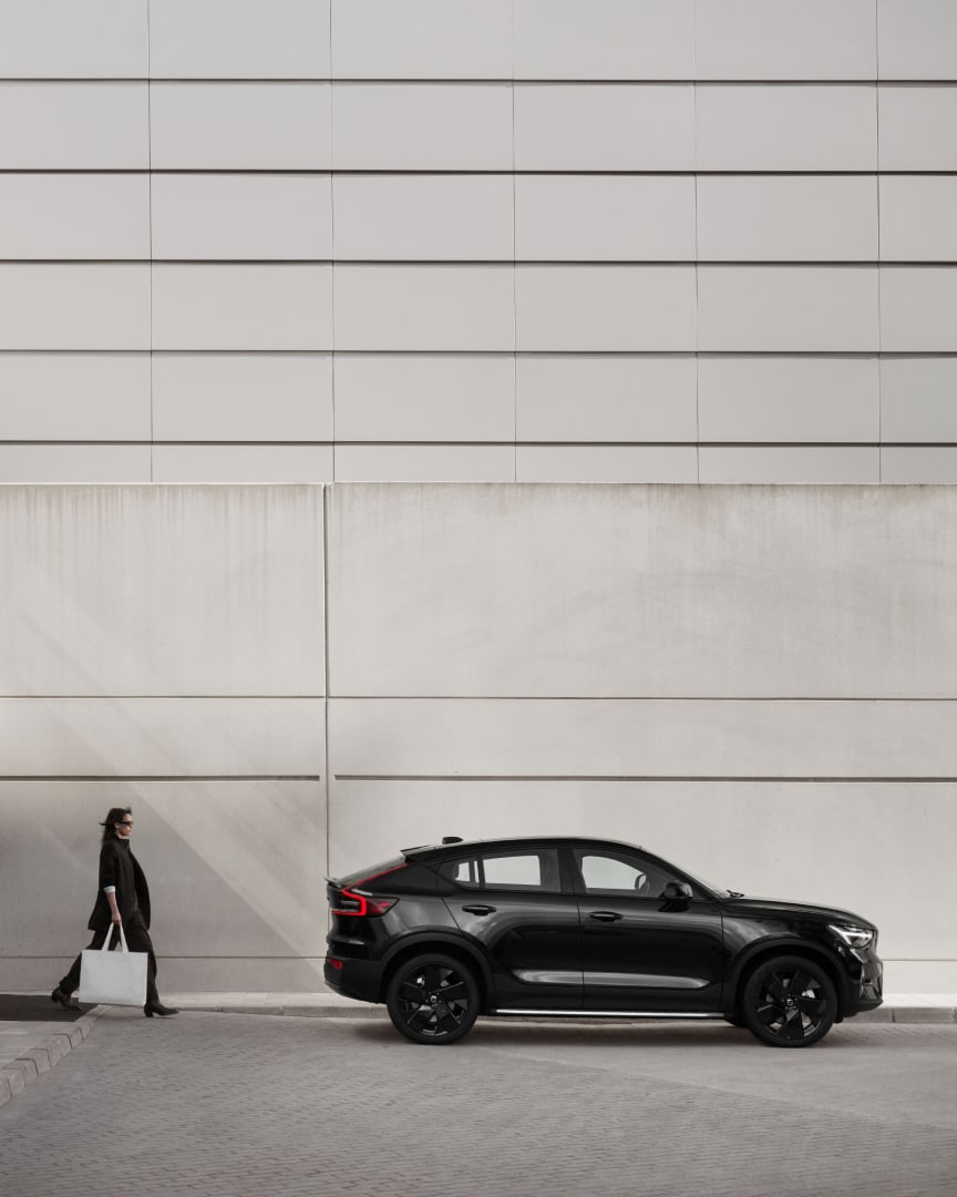 Una persona in piedi vicino alla Volvo EC40 Black Edition 100% elettrica.