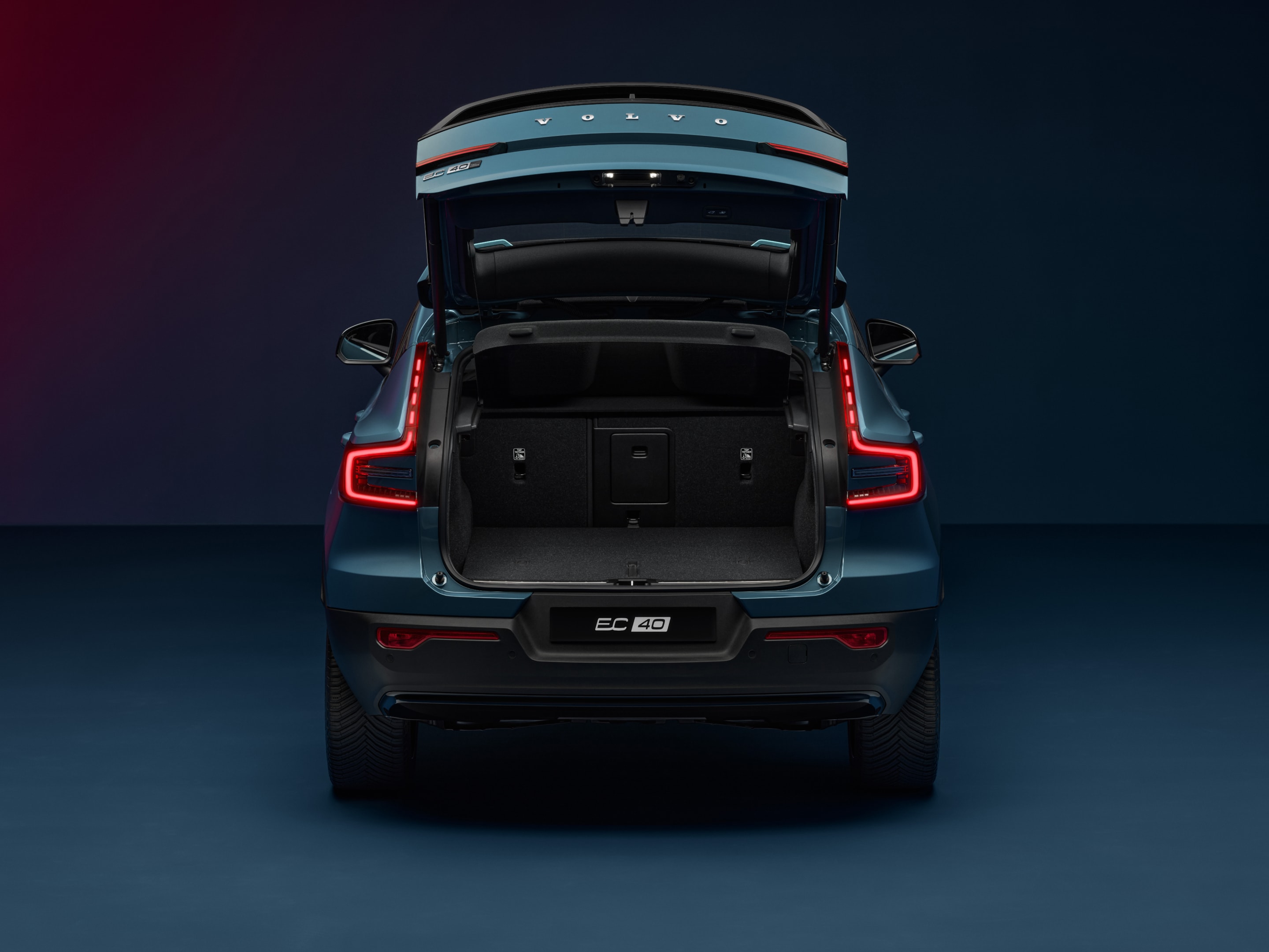 The open tailgate of the Volvo EC40 reveals a spacious and wide rear load compartment.