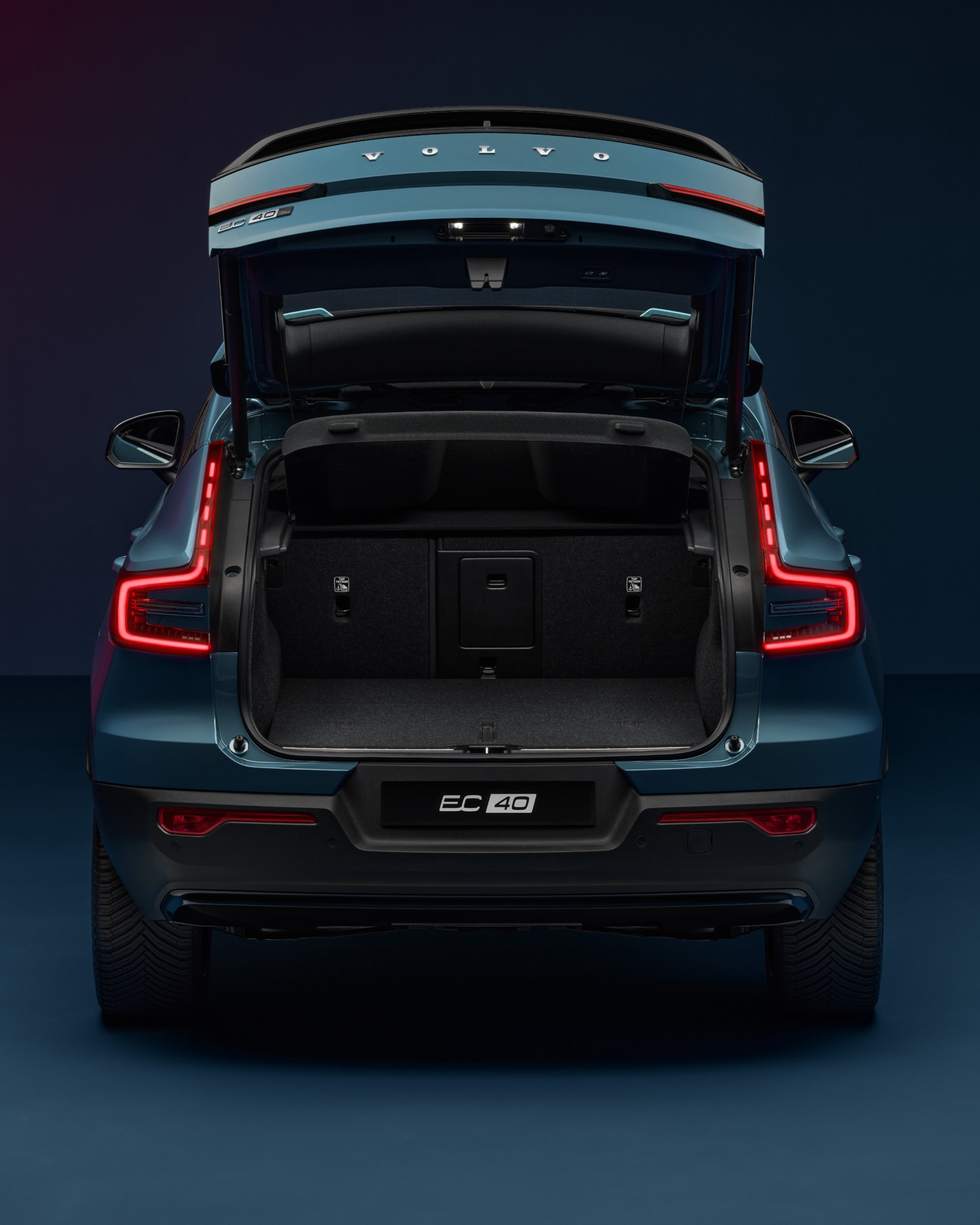 The open tailgate of the Volvo EC40 reveals a spacious and wide rear load compartment.