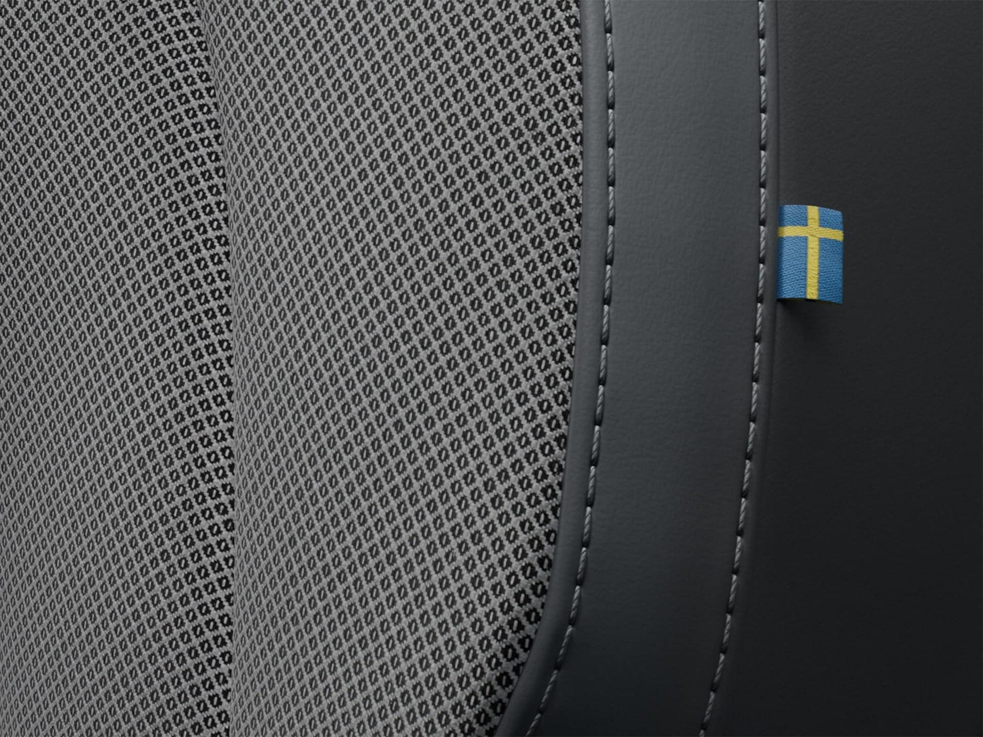 صورة مقربة لخياطة مقعد الراكب الأمامي في فولفو S60 الهجينة بالطاقة المساعدة، والتي تتميز بعلم سويدي صغير.