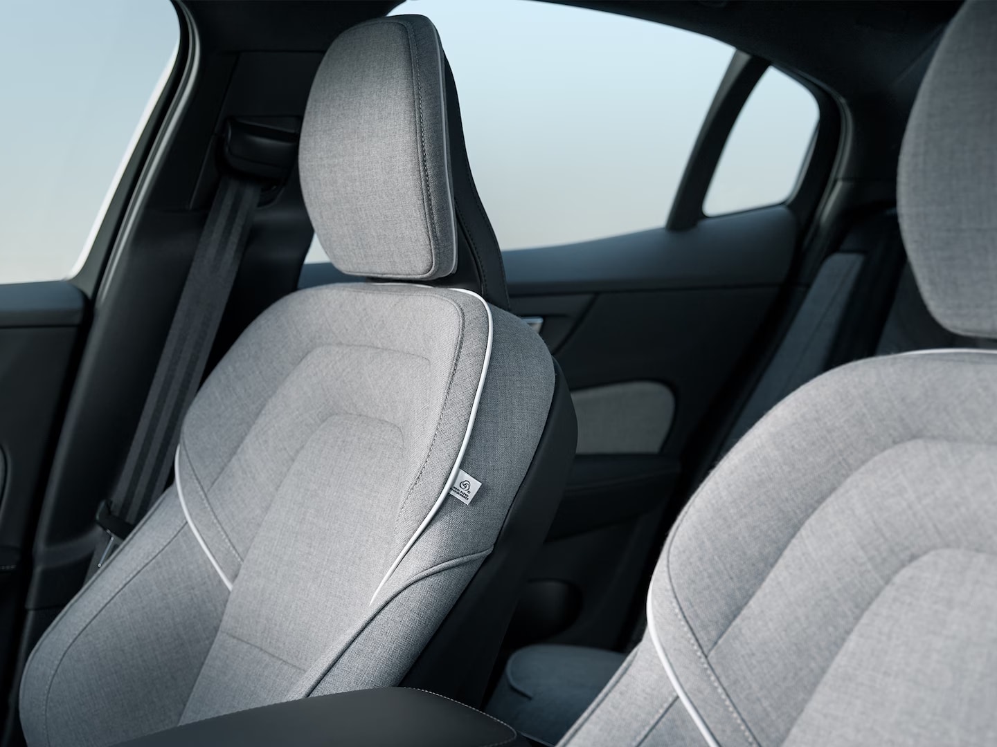 The Volvo S60 Recharge plug-in hybrid’s front passenger and driver’s seats in grey Tailored Wool Blend upholstery with white trim.