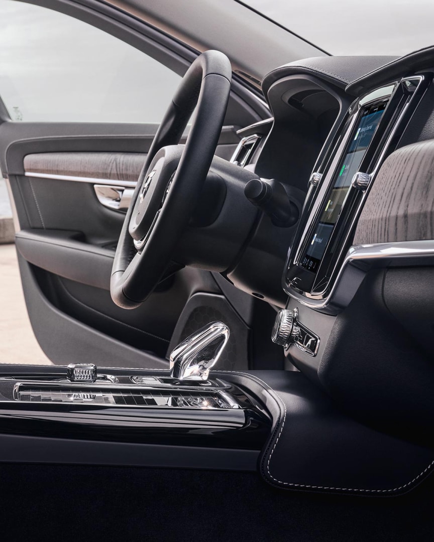 Interior view of the driver's seat, steering wheel, gear shifter and touchscreen centre display of a Volvo S90.