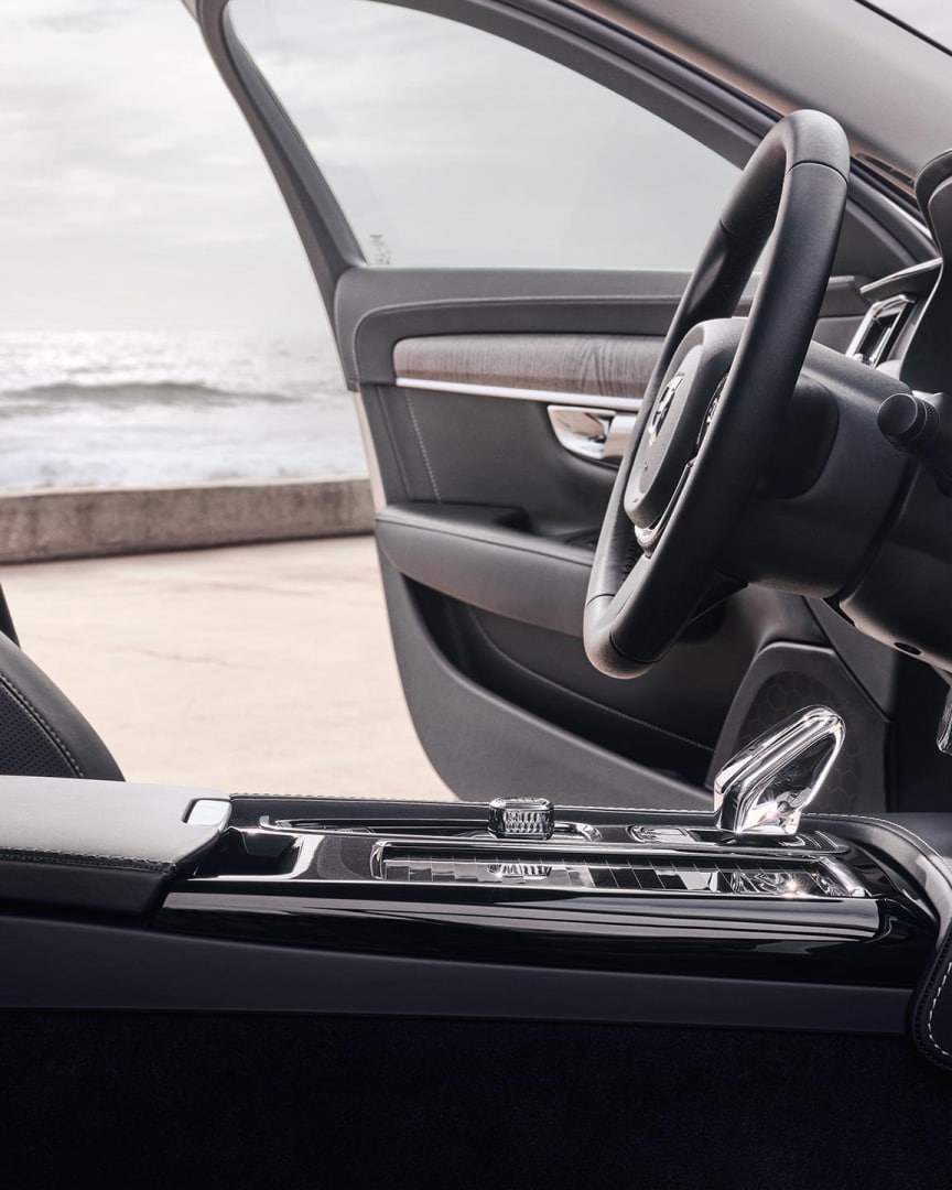 Interior view of the driver's seat, steering wheel, gear shifter and touchscreen centre display of a Volvo S90 Plug-in hybrid.