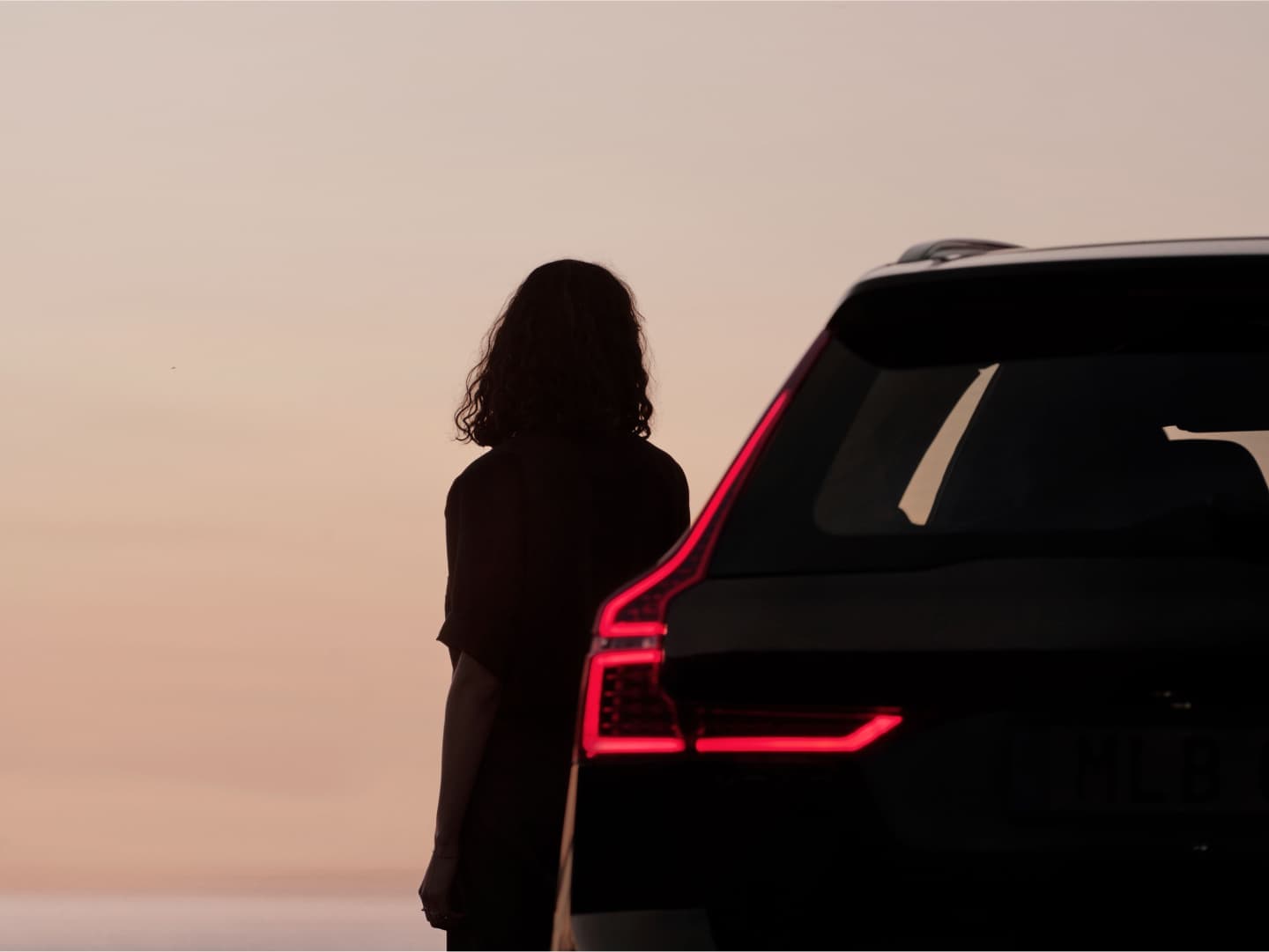 Een persoon staat naast de Volvo XC60 Black Edition mild hybrid.