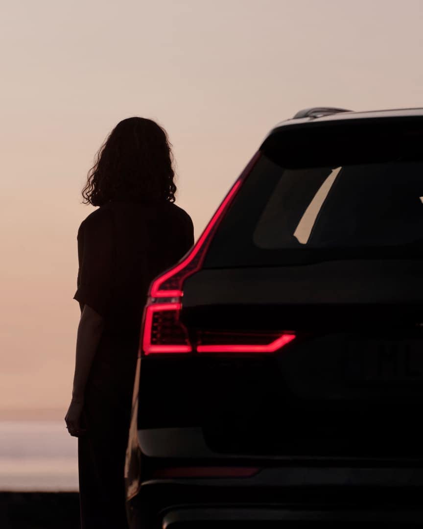 Een persoon staat naast de Volvo XC60 Black Edition mild hybrid.