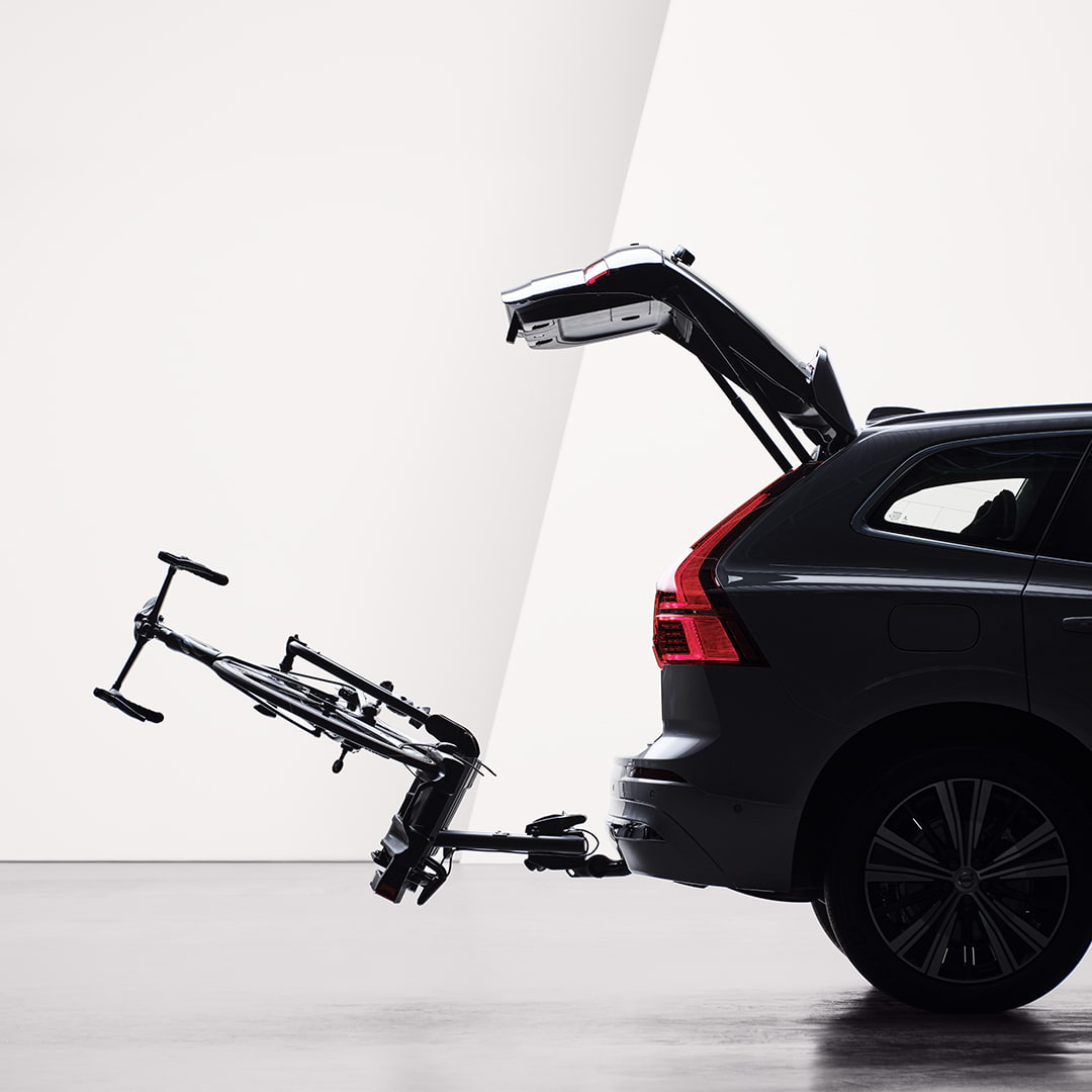 An open tailgate and a bicycle holder attached by tow bar folded down on the rear of a Volvo XC60. 