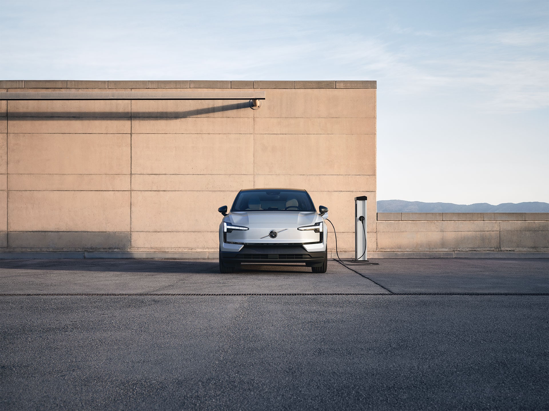 Un Volvo eléctrico cargándose en un poste de carga en el exterior.