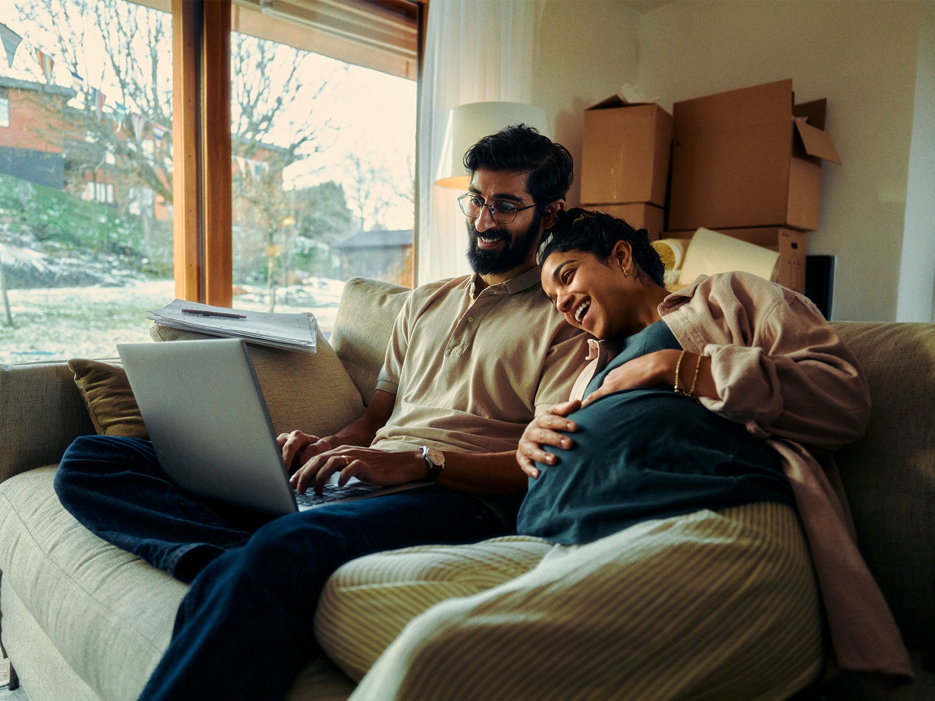 A young couple sitting down to calculate their cost savings on a laptop.