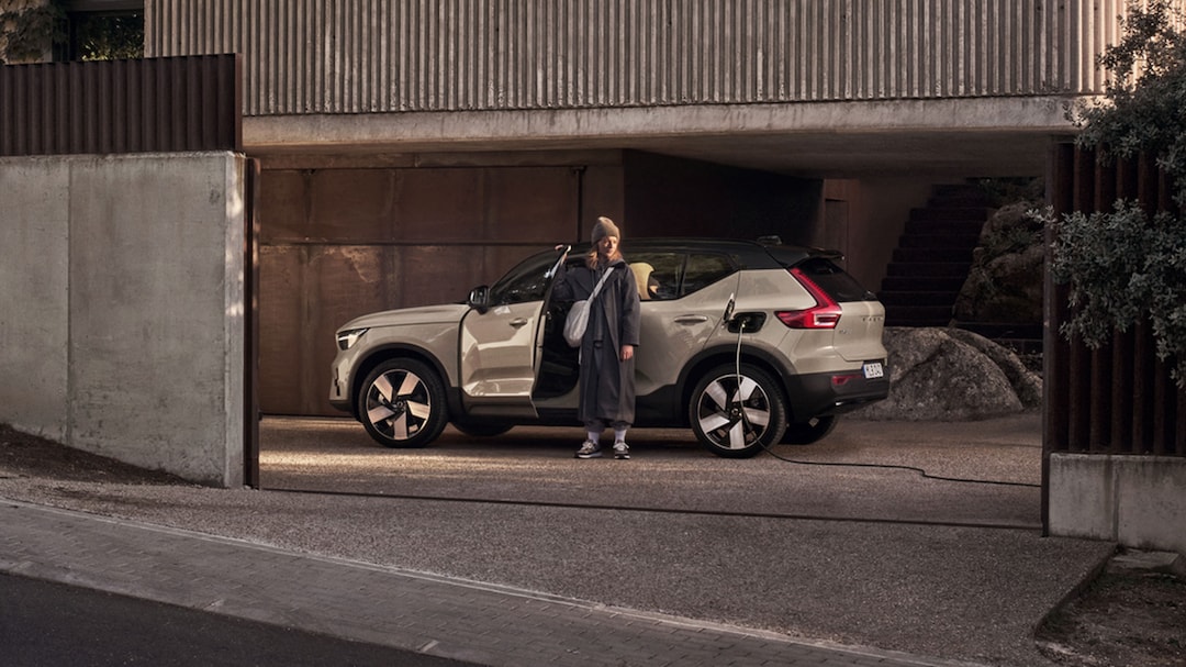 Femme devant un Volvo EX40 de profil garé