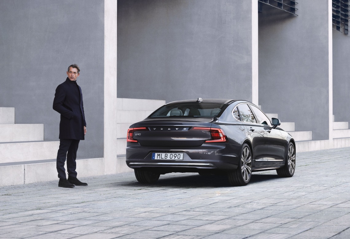 Mann steht neben einem Volvo S90 vor großen Treppen