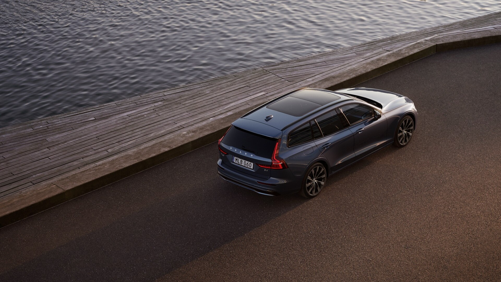 Volvo V60 fährt auf einer am Wasser gelegene Straße entlang