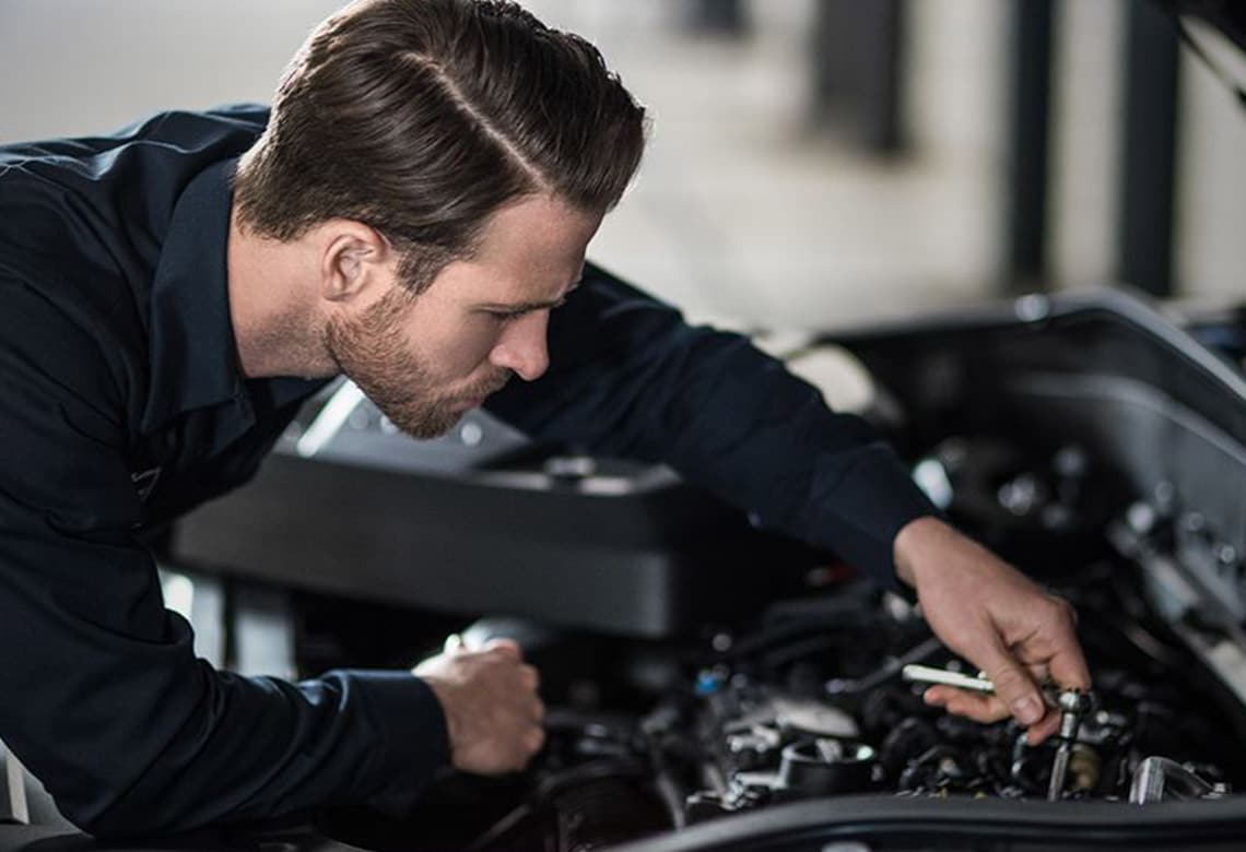 Volvo Service - Kfz-Mechaniker arbeitet unter der Motorhaube eines Volvo