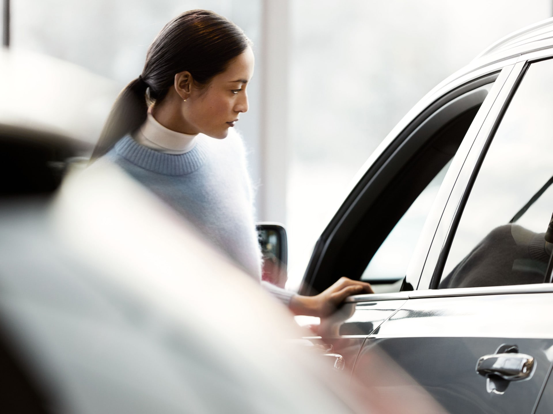 Una mujer en un concesionario mirando un SUV de Volvo