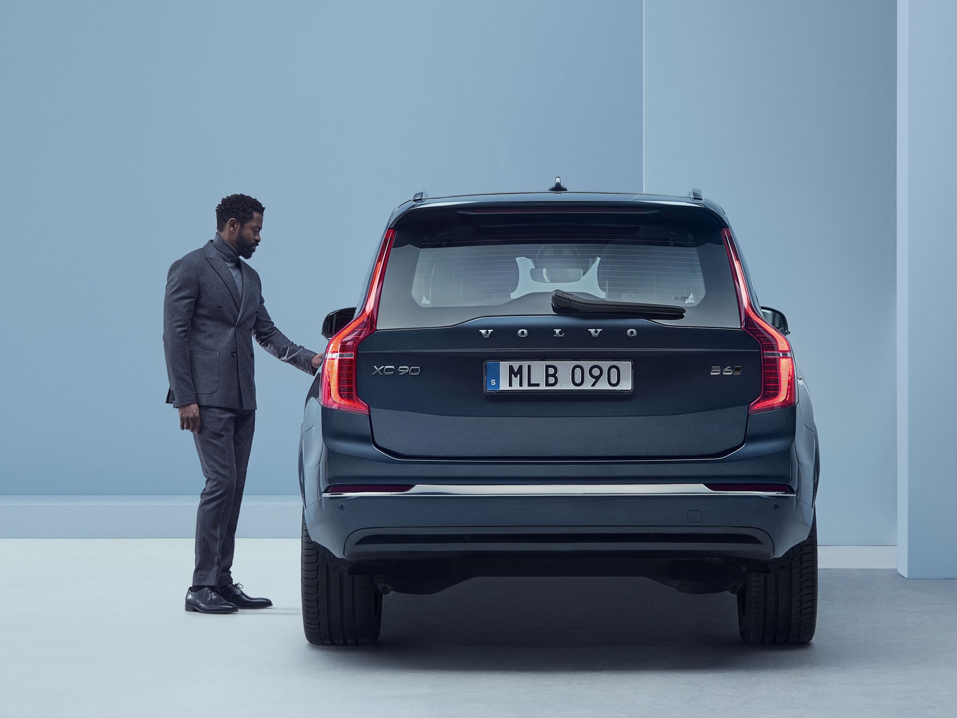 Un hombre junto a un Volvo XC90 vista trasera