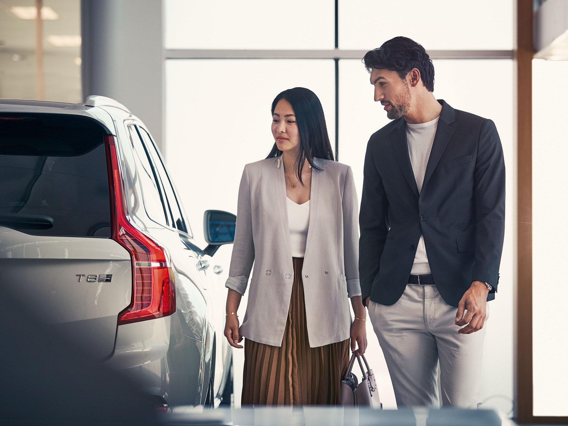 Un hombre y una mujer observando de cerca un Volvo XC90