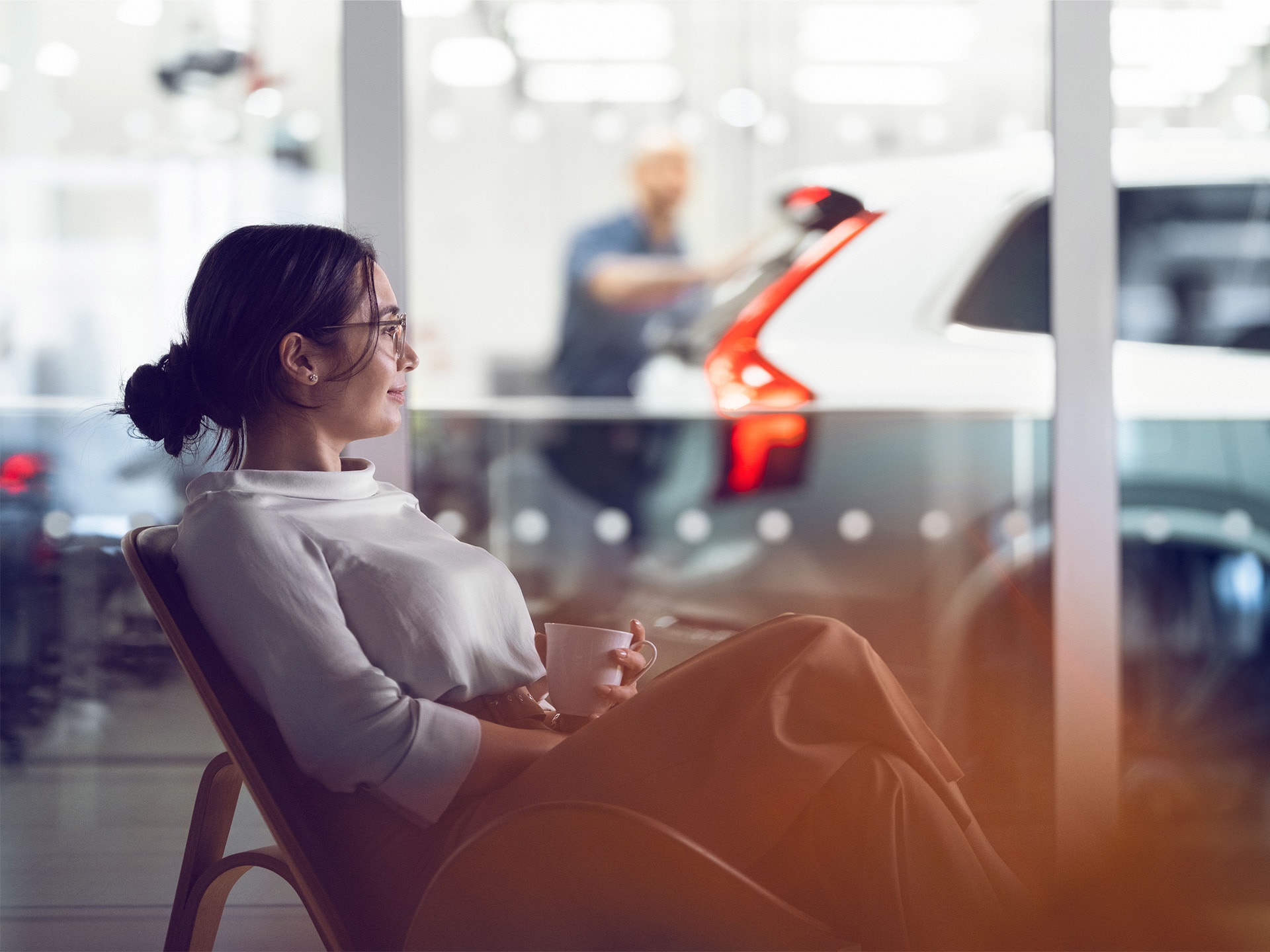 Mujer con una taza esperando en un concesionario Volvo