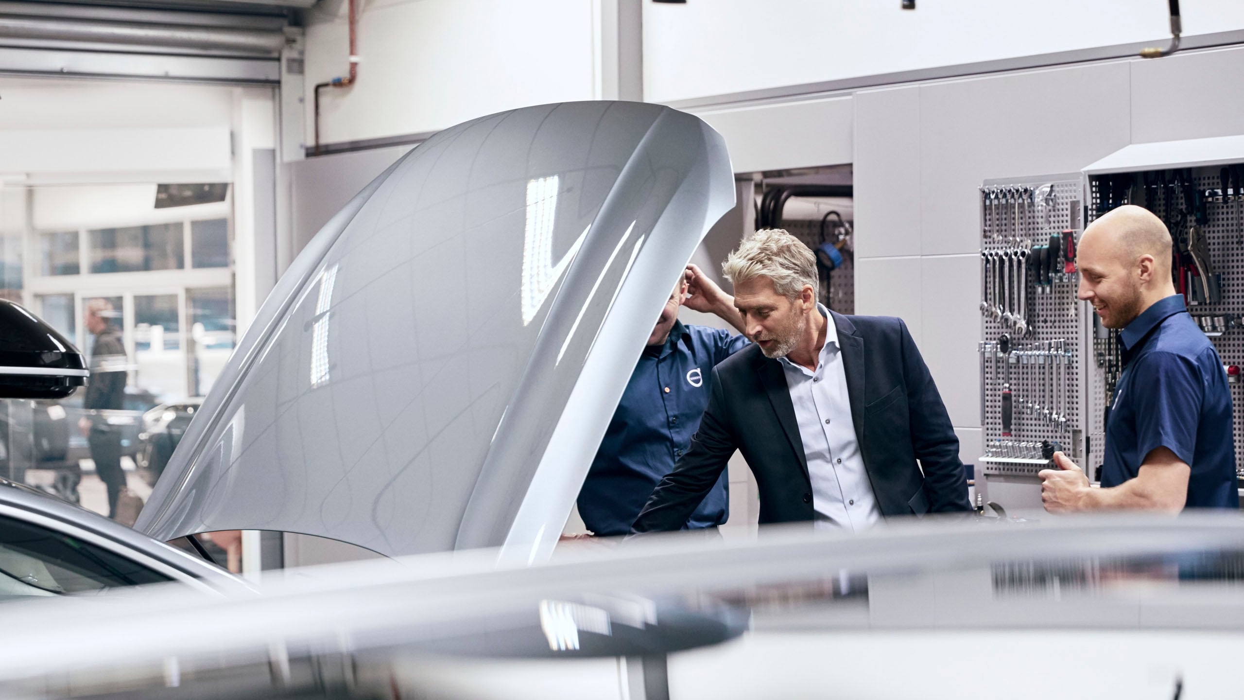 Cliente y mecánicos mirando el interior de un Volvo