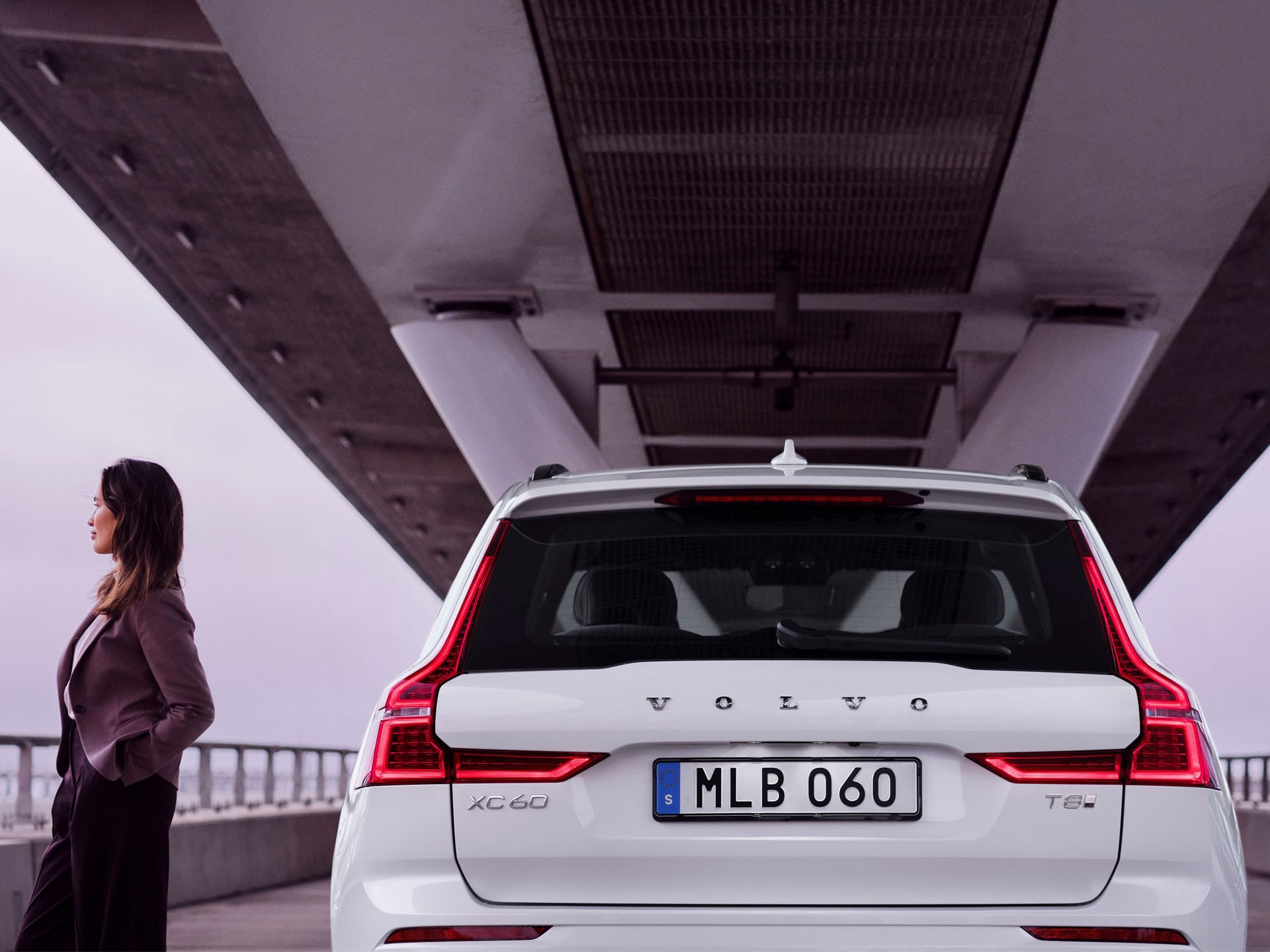 Una mujer junto a un Volvo XC60 bajo un puente