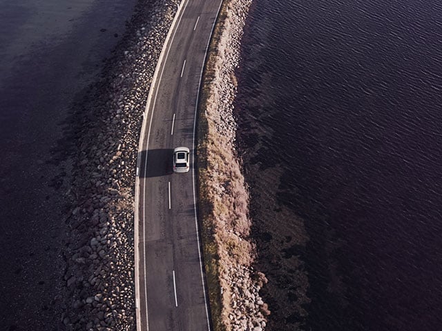 Vit Volvo från ovan som kör på väg vid hav