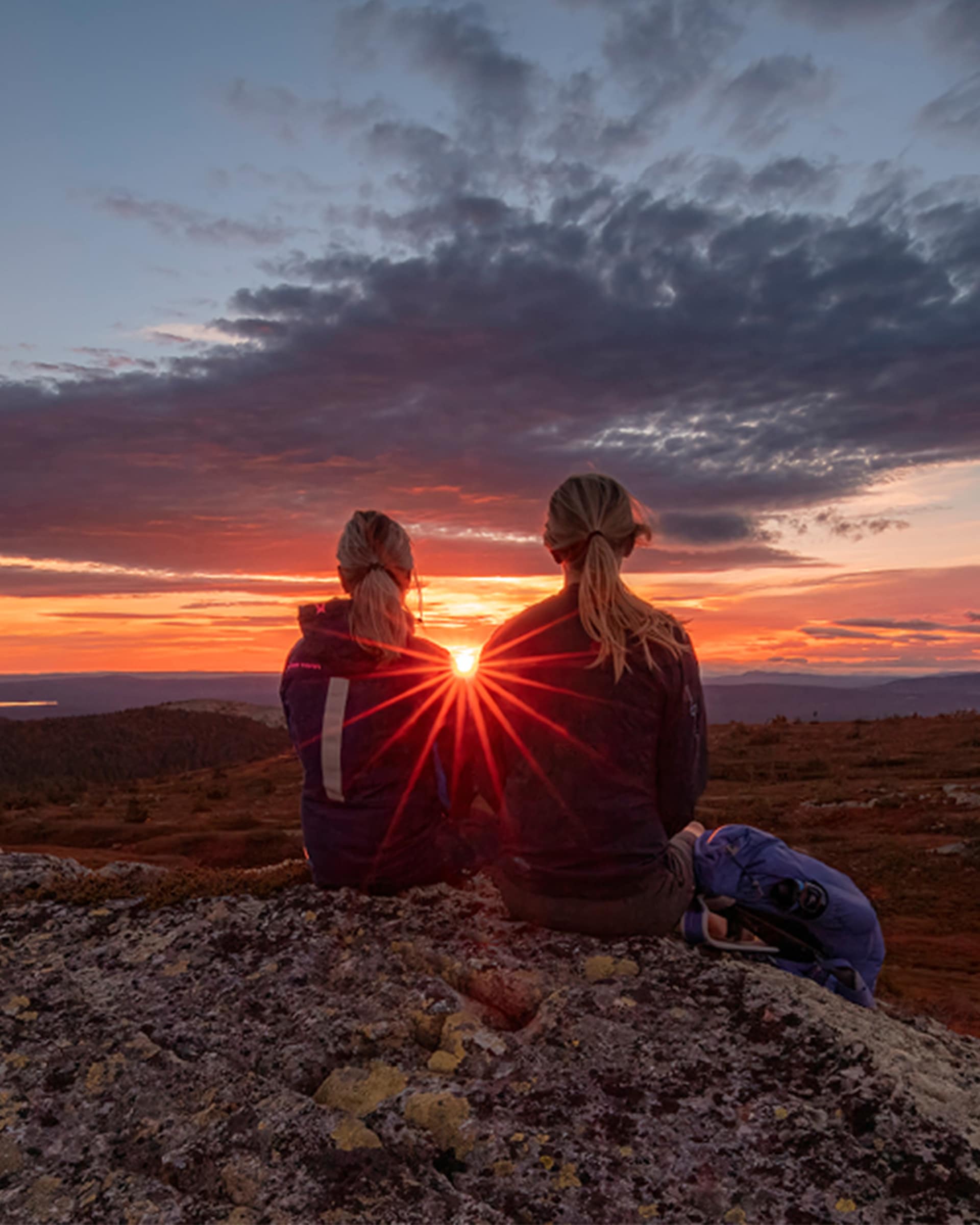 Två kvinnor sitter på bergsklippa 