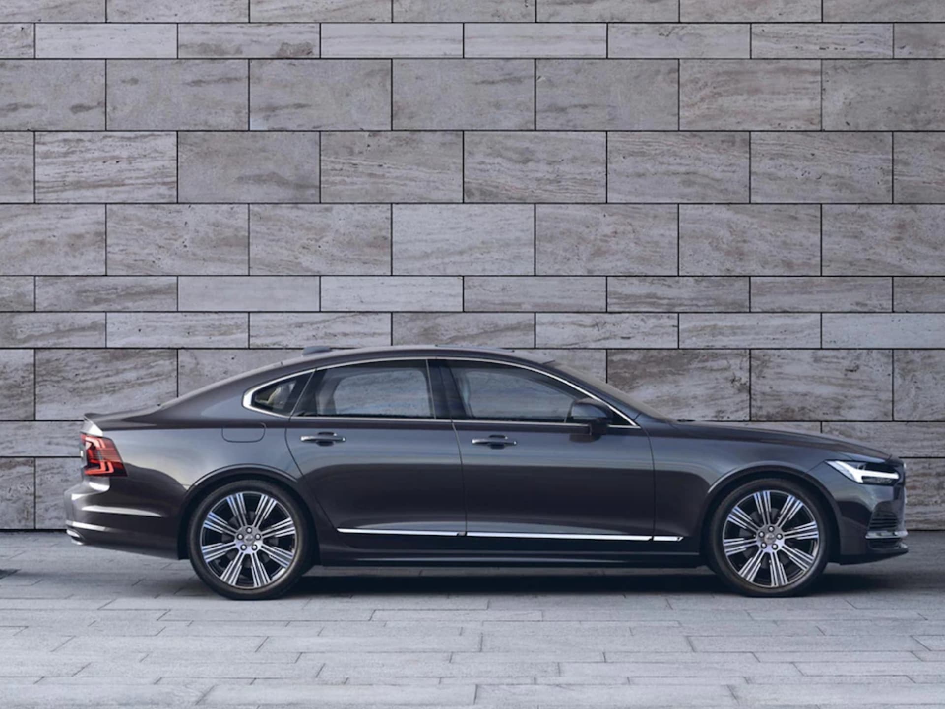 Une Volvo S90 noire devant une façade de pierre