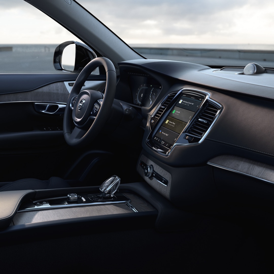 Passenger view of the Volvo XC90 Recharge plug-in hybrid driver’s seat and door in wool upholstery and black steering wheel.