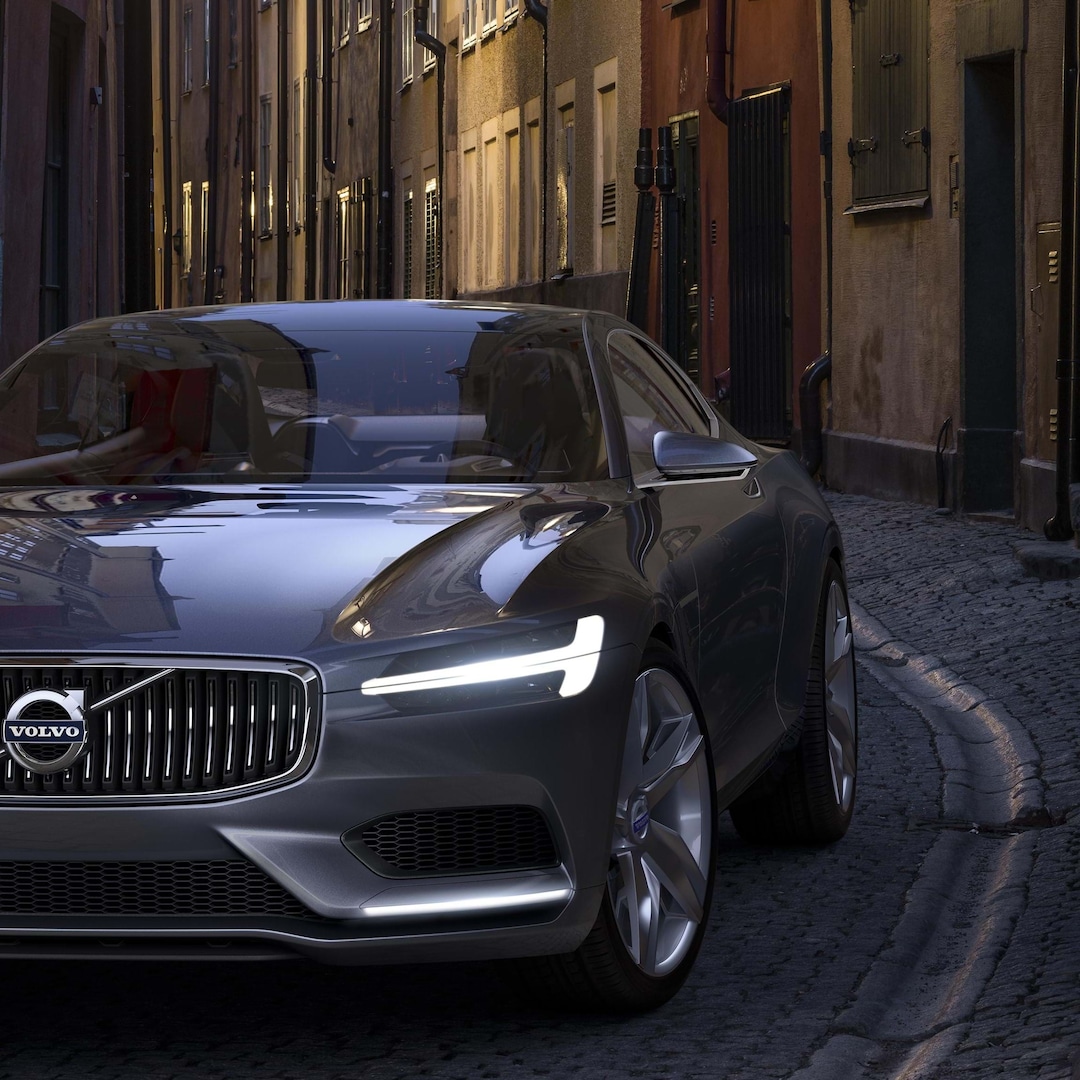 Concept Coupé Volvo gris recorriendo una calle urbana empedrada