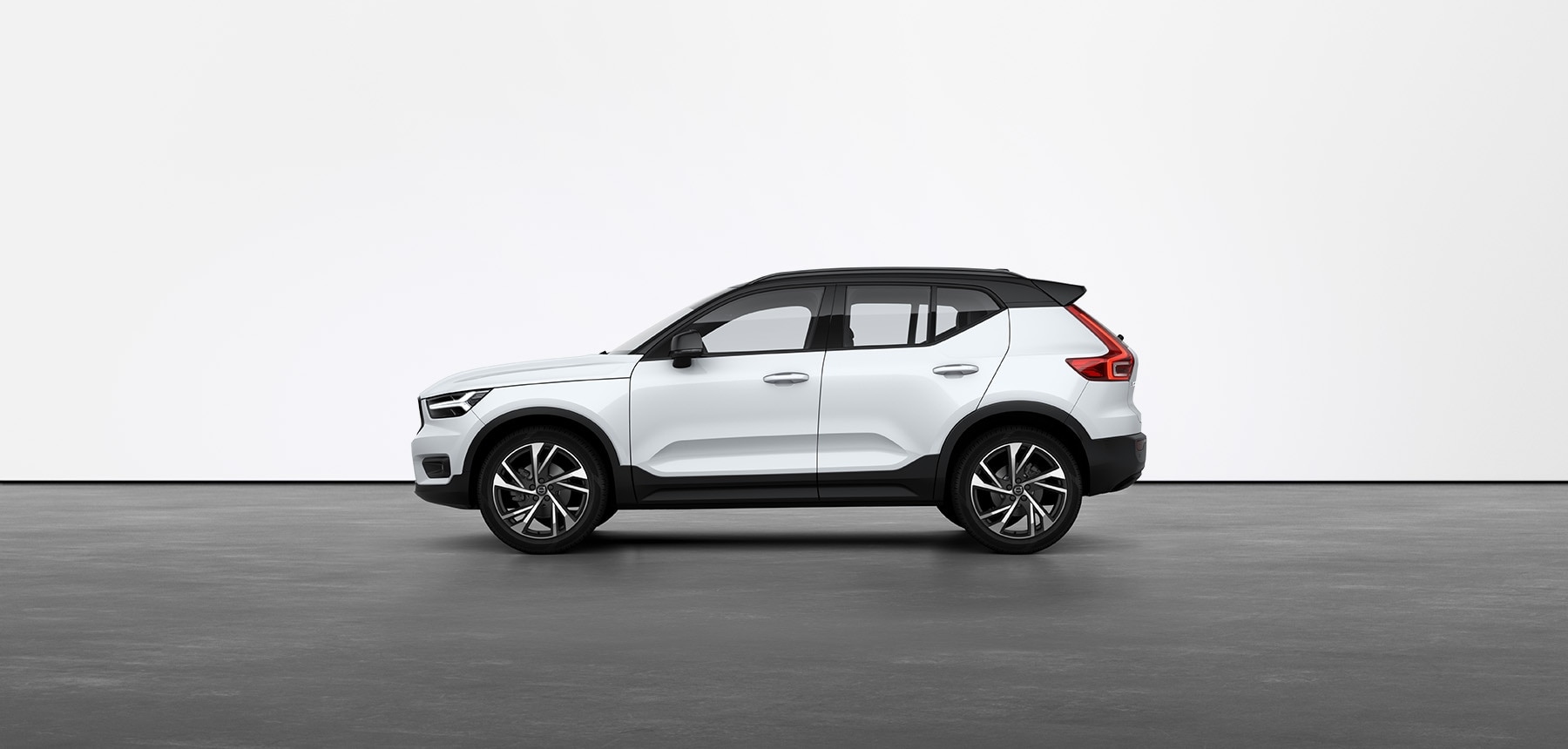 A white Volvo XC40 standing still on grey floor in a studio