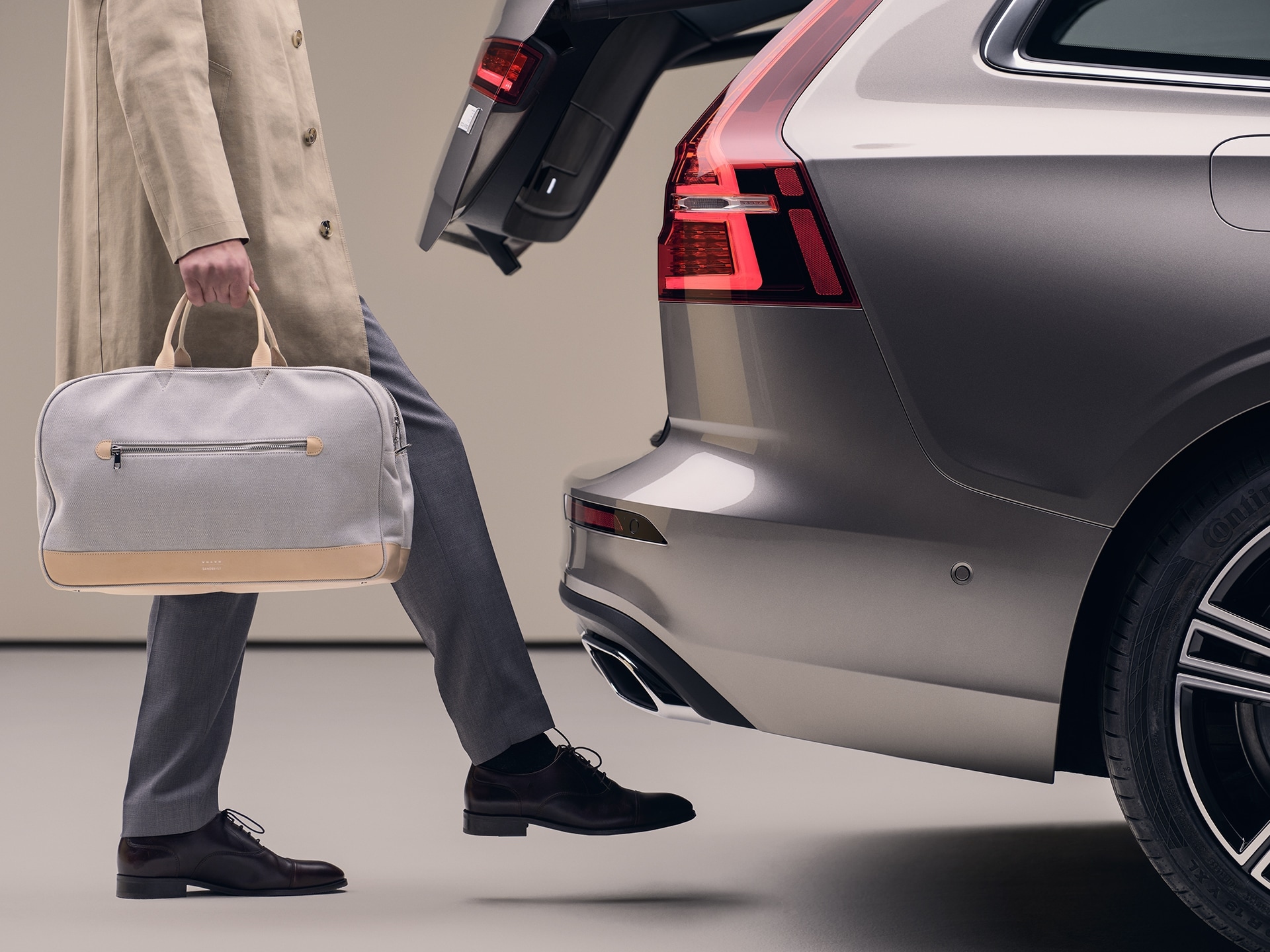 A man with a sports bag in his hand moves his foot under the rear bumper to open the hands-free tailgate.